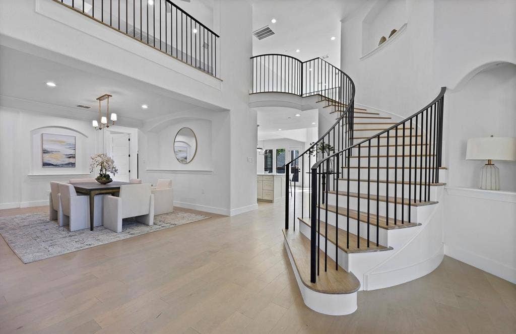 1750 Greenwood Court, Prosper, TX 75078 Curved staircase with black iron balusters, high ceilings, wood-finish flooring, recessed lighting, and a dining area with a chandelier