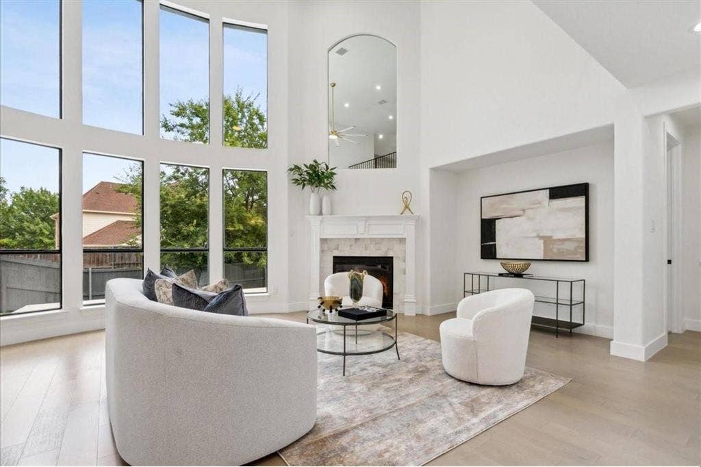1750 Greenwood Court, Prosper, TX 75078 Soaring ceilings, expansive window wall, light wood-finish flooring, fireplace with stone surround, and a white mantel