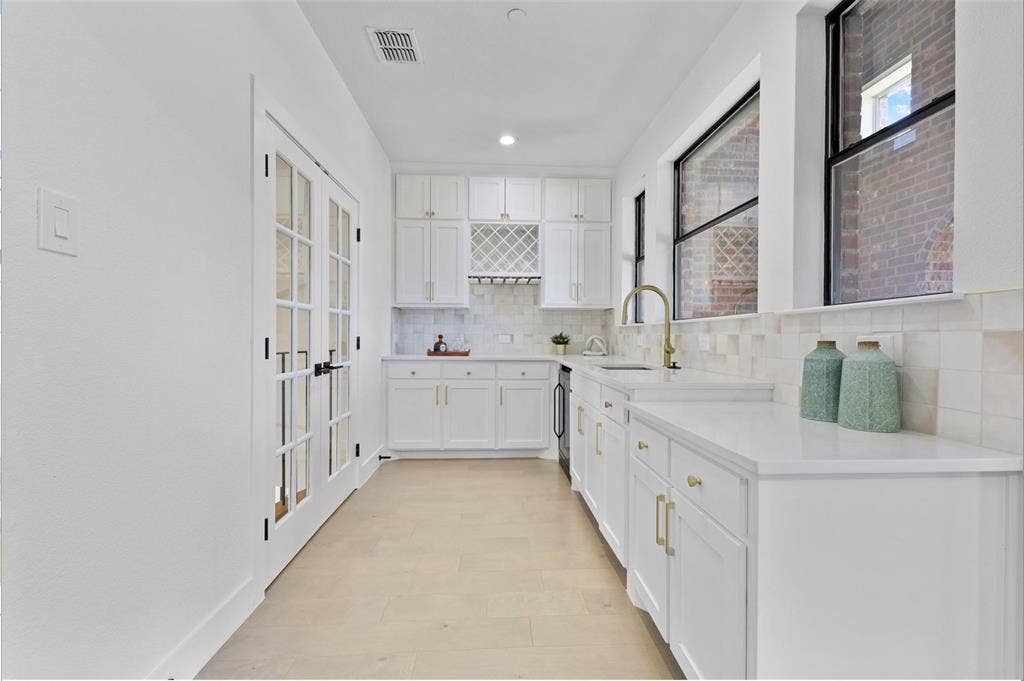 1750 Greenwood Court, Prosper, TX 75078 Full kitchen featuring white cabinetry, light-toned countertops, a built-in wine rack, and a gold-finish faucet