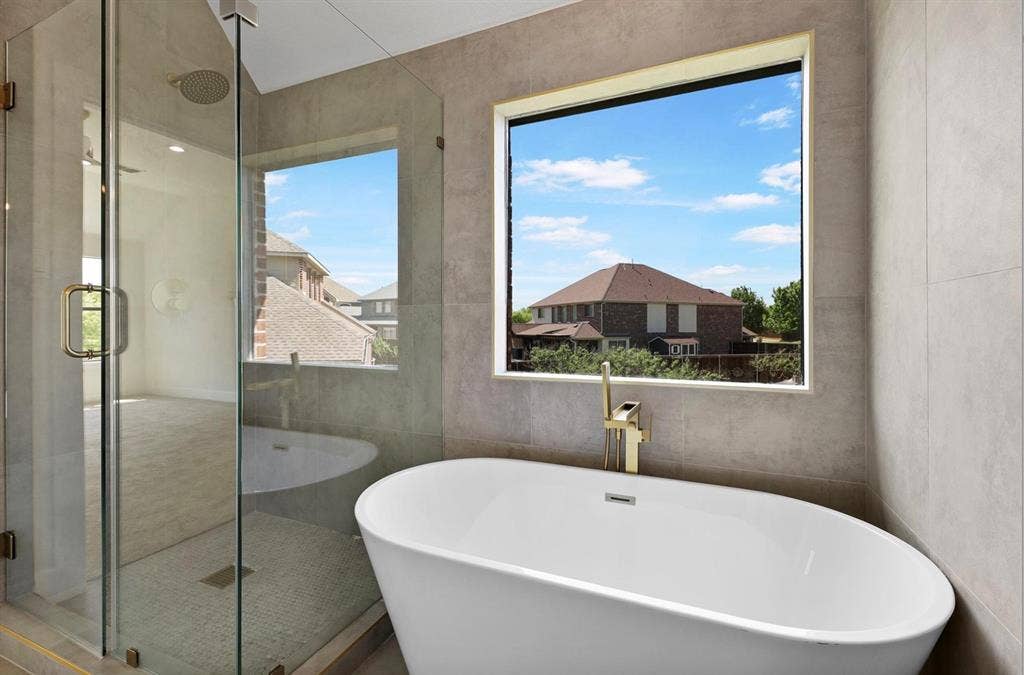 1750 Greenwood Court, Prosper, TX 75078 Freestanding soaking tub with a gold-tone faucet, walk-in glass shower, and large window