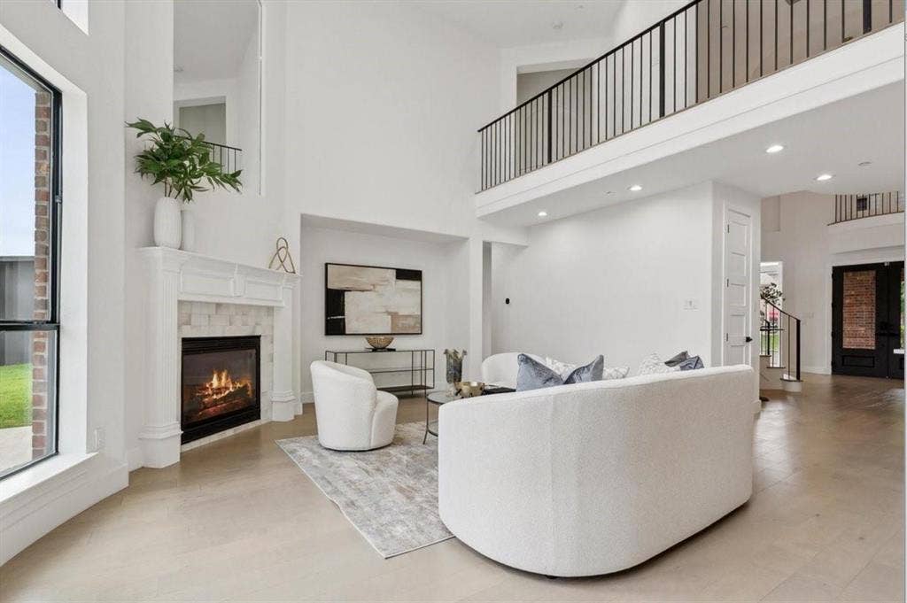 1750 Greenwood Court, Prosper, TX 75078 Two-story living area with high ceilings, featuring a gas fireplace with a white mantel and tile surround