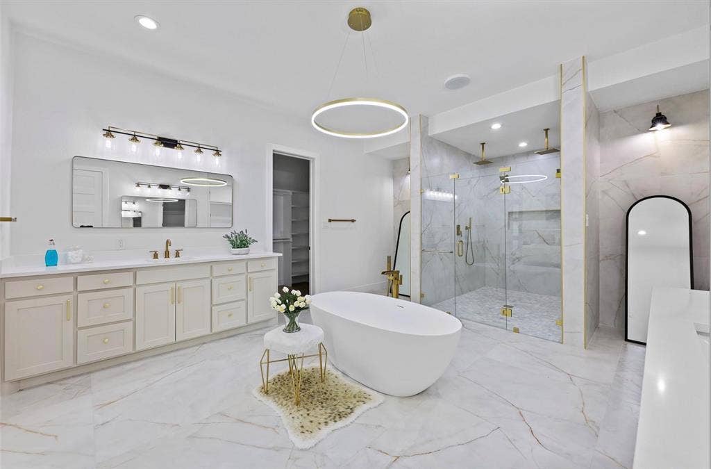 1750 Greenwood Court, Prosper, TX 75078 Spacious bathroom featuring a freestanding soaking tub, dual vanity with undermount sinks, glass-enclosed shower with multiple shower heads, and large format marble-look tile flooring