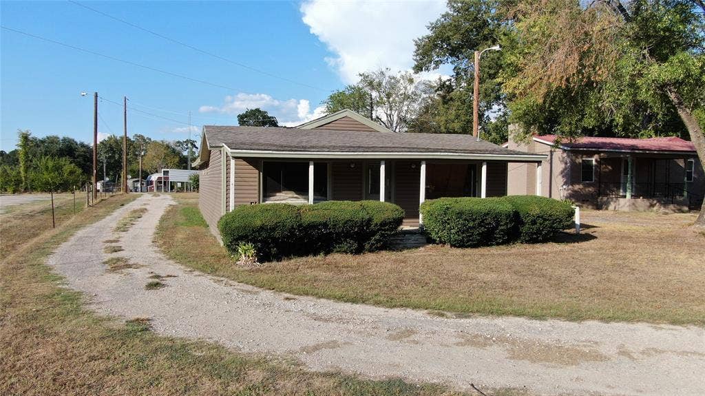 7544 N US HIGHWAY 69 Highway, Alba, TX 75410 Siding exterior with covered porch, gravel driveway, and mature landscaping