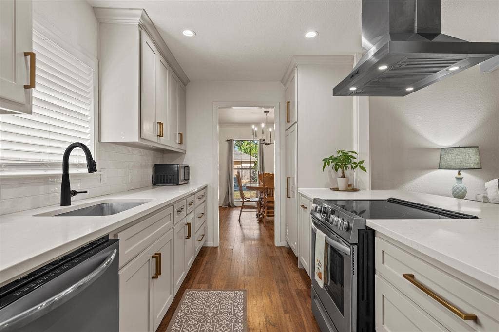1712 Laurel Lake Drive, Waco, TX 76710 Galley kitchen featuring white cabinetry, light countertops, wood-finish flooring, a stainless steel range hood, and a black faucet