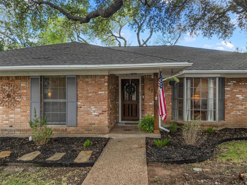 1712 Laurel Lake Drive, Waco, TX 76710 Brick facade with a dark shingle roof, a paneled wood entry door, and a bay window