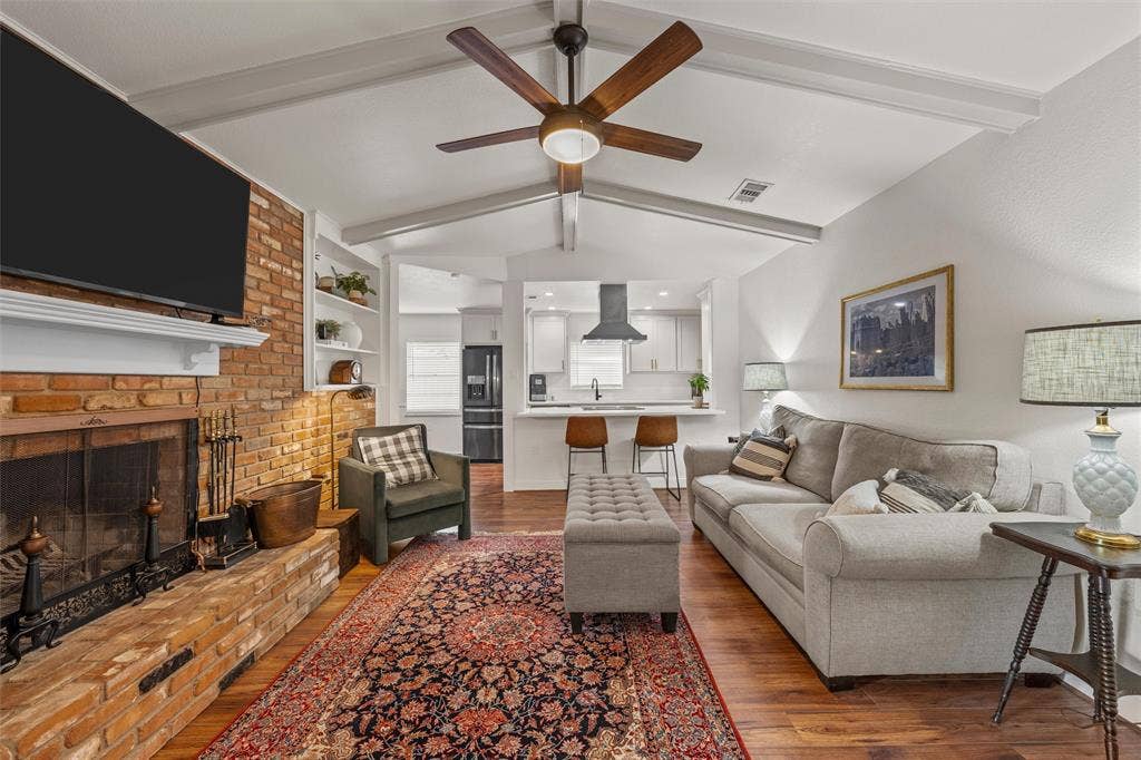 1712 Laurel Lake Drive, Waco, TX 76710 Vaulted ceiling with exposed beams, brick fireplace with mantel, wood-finish flooring, built-in shelving, and a modern ceiling fan