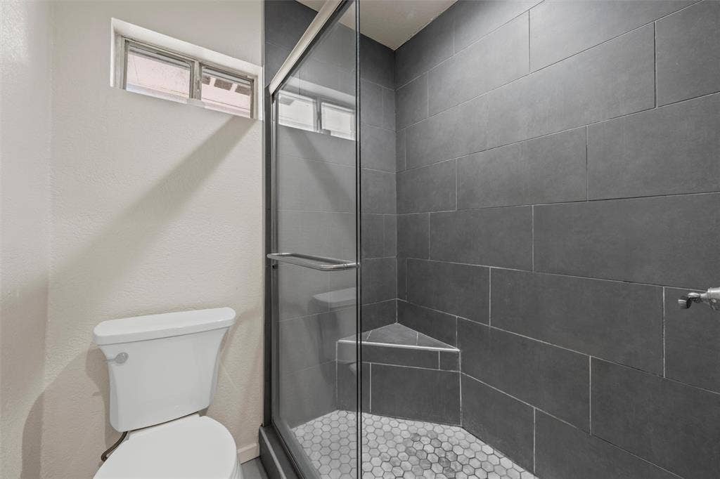 1712 Laurel Lake Drive, Waco, TX 76710 Shower with glass enclosure, dark gray tile walls, and a hexagonal mosaic tile floor
