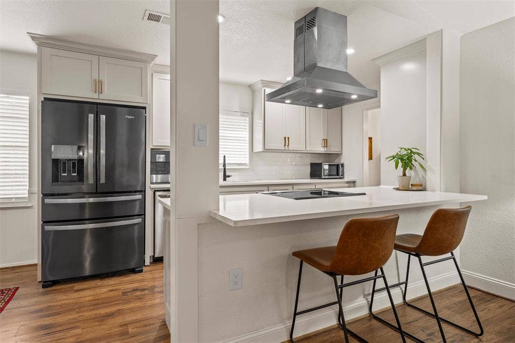 1712 Laurel Lake Drive, Waco, TX 76710 Kitchen featuring wood-finish flooring, light-toned cabinetry, stainless steel range hood, built-in cooktop, and a white countertop