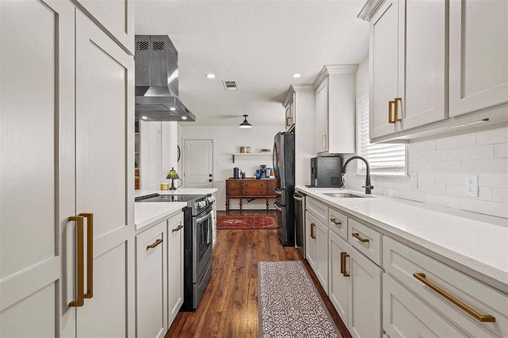 1712 Laurel Lake Drive, Waco, TX 76710 Galley kitchen featuring white shaker cabinetry, white countertops, stainless steel appliances, wood-finish flooring, and subway tile backsplash