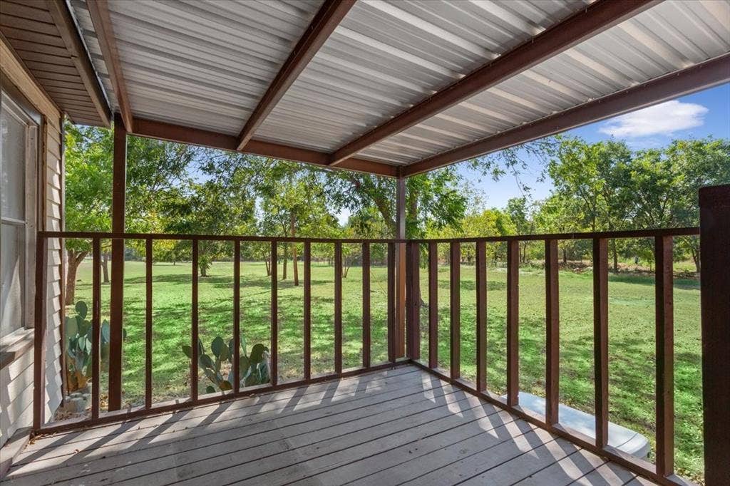 4246 Old Caufield Ranch Road, McGregor, TX 76657 Covered porch with wood decking, metal roof, and wood railings overlooking a grassy expanse with mature trees