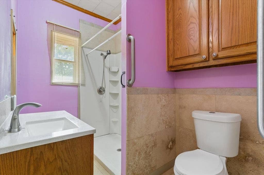 4246 Old Caufield Ranch Road, McGregor, TX 76657 Vanity with integrated sink, wood-finish cabinetry, walk-in shower, and wall-mounted storage cabinets