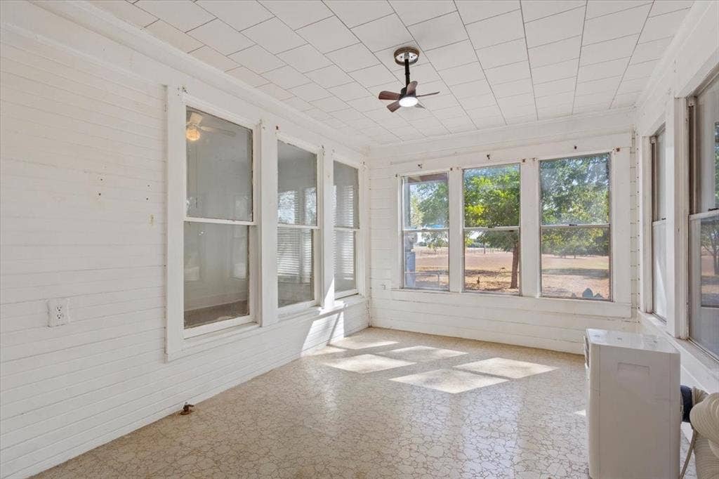 4246 Old Caufield Ranch Road, McGregor, TX 76657 Enclosed room adding another bedroom to this property which features multiple windows, paneled walls, and a small ceiling fan for air circulation