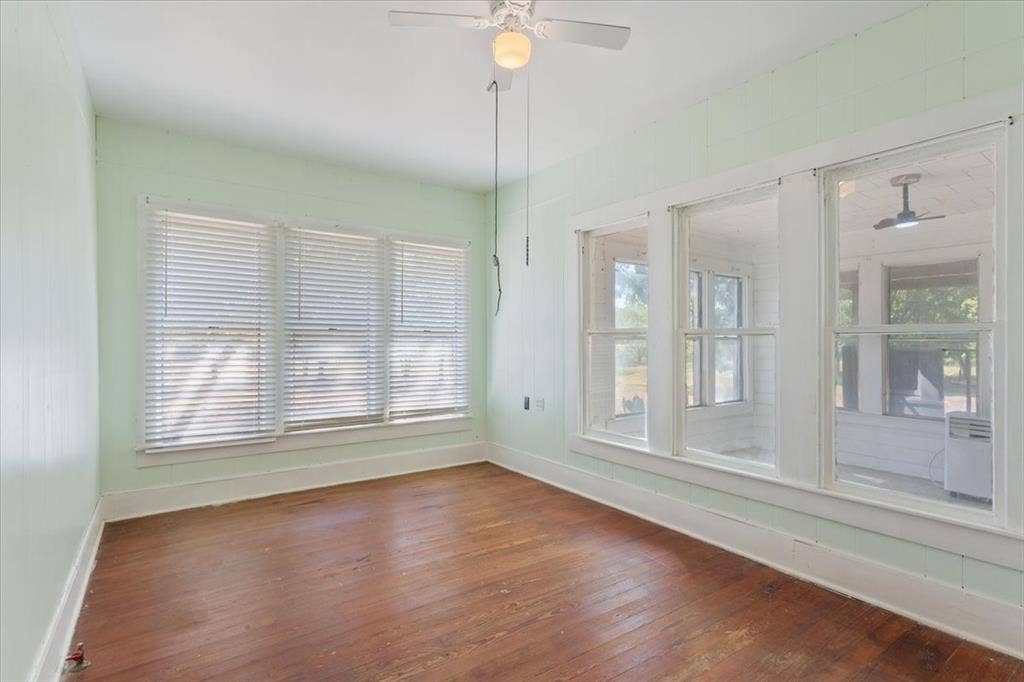 4246 Old Caufield Ranch Road, McGregor, TX 76657 Hardwood flooring, painted walls, ceiling fan, multiple windows with blinds, and white trim
