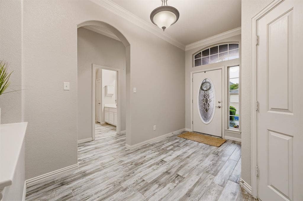 307 Park Haven Boulevard, Euless, TX 76039 Welcoming entryway showcasing wood-finish plank flooring, arched architectural details, and abundant natural light from transom-topped entry door