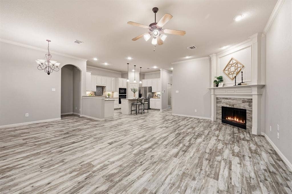 307 Park Haven Boulevard, Euless, TX 76039 Wood-finish flooring throughout, featuring a fireplace with stone surround and mantle, crown molding, a ceiling fan, and recessed lighting