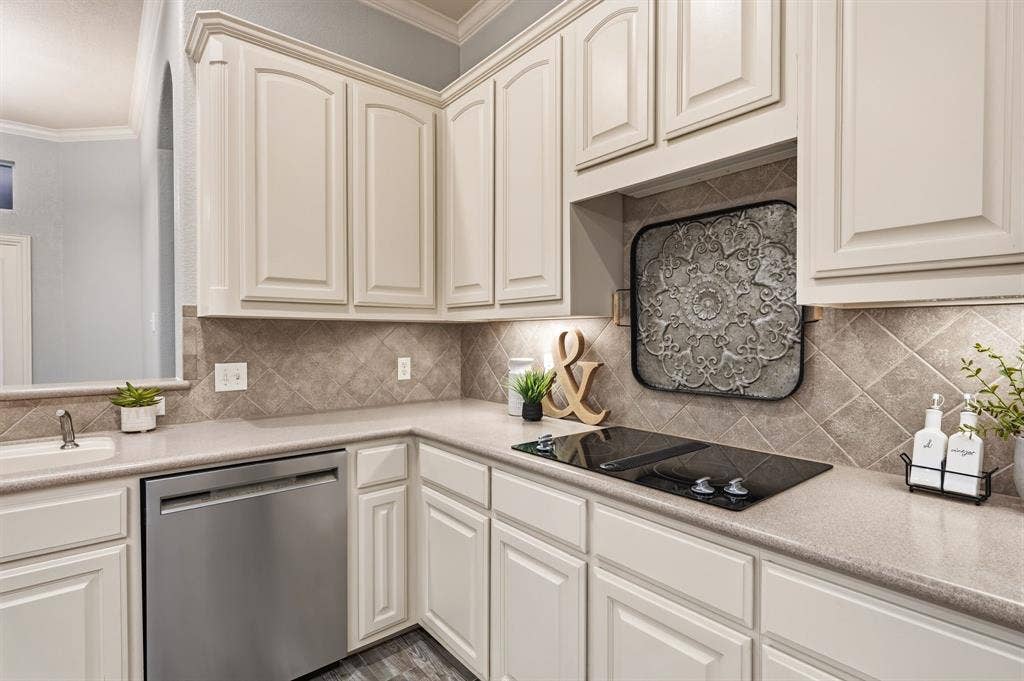 307 Park Haven Boulevard, Euless, TX 76039 Built-in stainless steel dishwasher, integrated cooktop, light-toned cabinetry with panel detailing, light-toned countertops, and diagonal tile backsplash