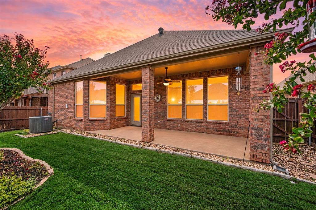 307 Park Haven Boulevard, Euless, TX 76039 Brick exterior with covered patio featuring a ceiling fan, multiple windows, and a manicured lawn