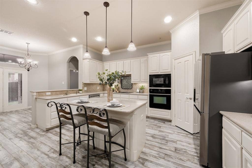 307 Park Haven Boulevard, Euless, TX 76039 Kitchen featuring an island with pendant lighting, wood-finish flooring, built-in appliances, and white cabinetry