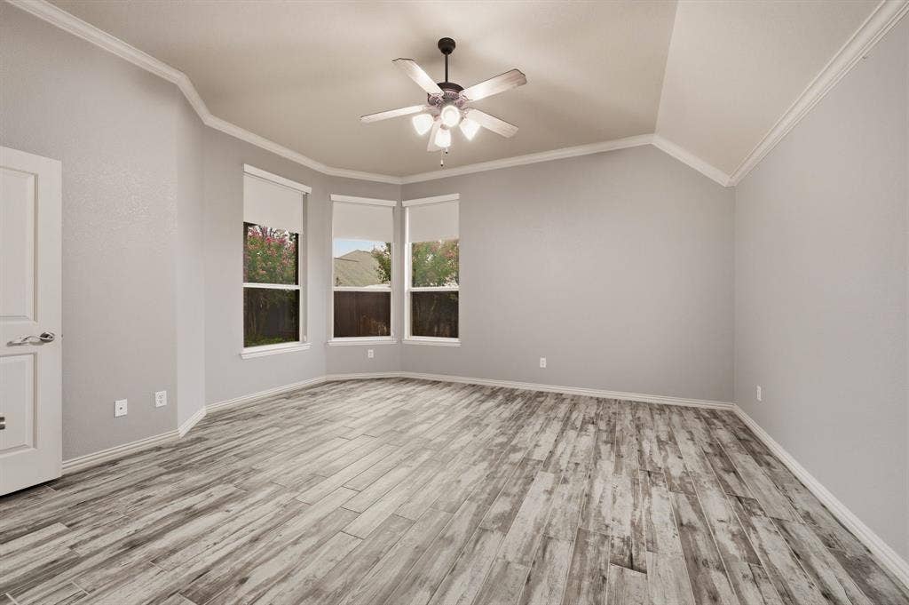 307 Park Haven Boulevard, Euless, TX 76039 Vaulted ceiling with crown molding, wood-finish flooring, ceiling fan with integrated lighting, and a bay window featuring roller blinds
