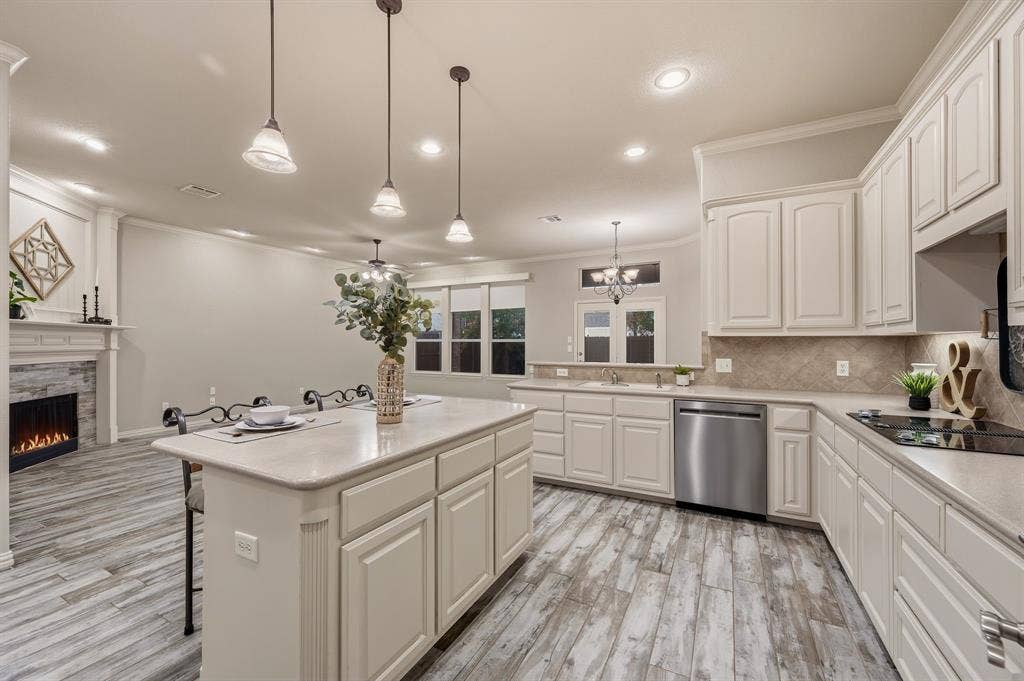 307 Park Haven Boulevard, Euless, TX 76039 Kitchen island with countertop seating, wood-finish flooring, electric fireplace with stone surround, recessed lighting, and stainless steel appliances