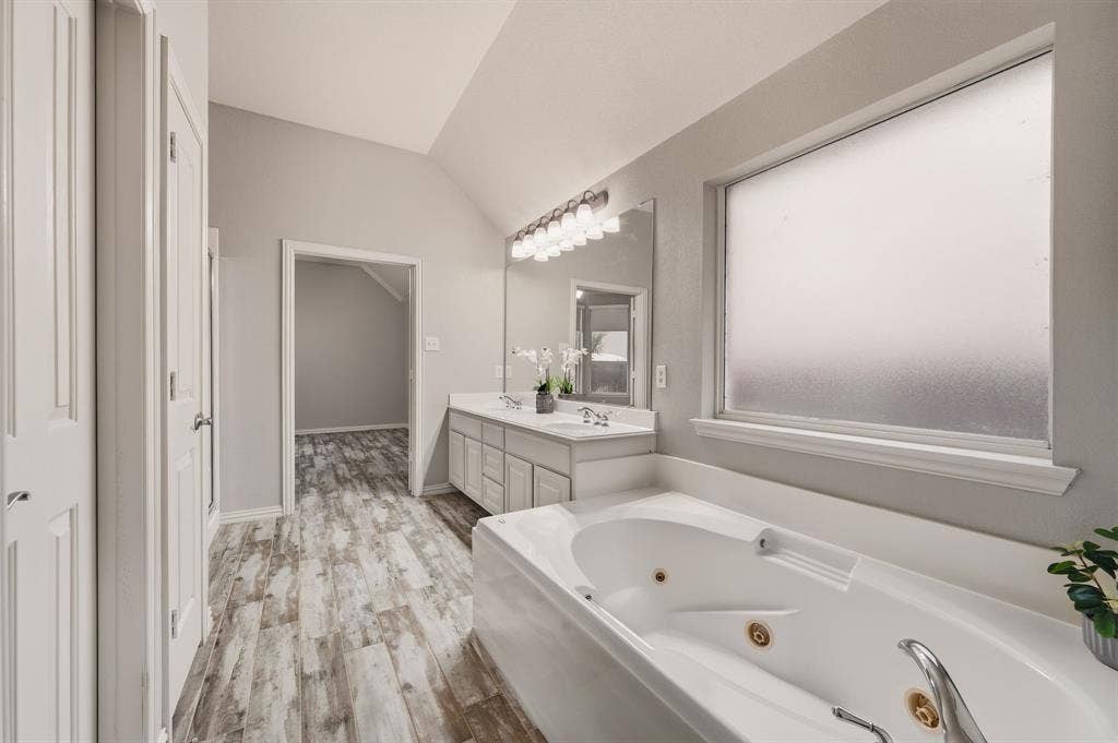 307 Park Haven Boulevard, Euless, TX 76039 Vaulted ceiling, dual vanity with undermount sinks, wood-finish flooring, white soaking tub with jets, and frosted window