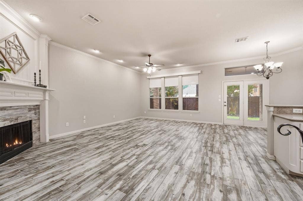 307 Park Haven Boulevard, Euless, TX 76039 Spacious living area featuring wood-look flooring, a stone-faced fireplace with a white mantel, multiple windows, and a glass-paneled door