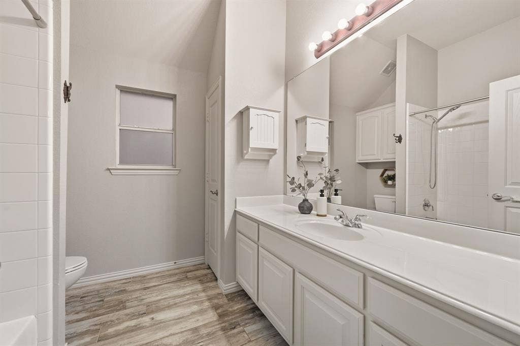 307 Park Haven Boulevard, Euless, TX 76039 Extended vanity with integrated sink, wood-finish flooring, a combination shower and tub, and a large wall-mounted mirror
