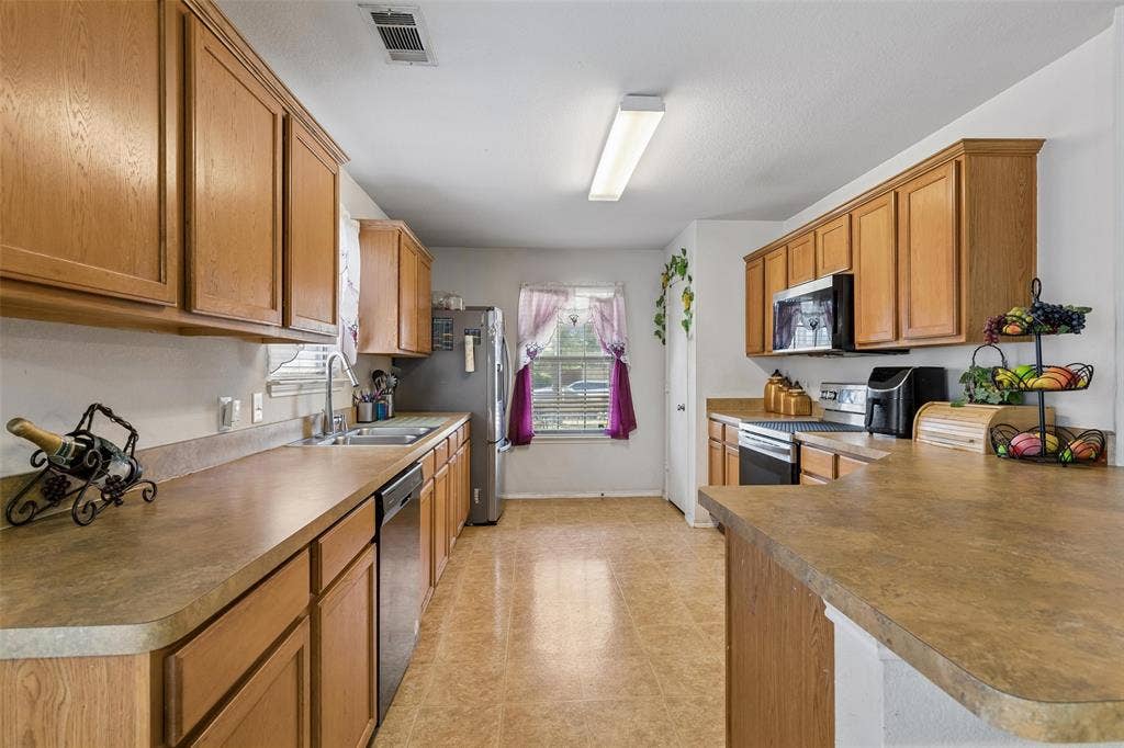 3118 Rosslynn Court, Seagoville, TX 75159 Wood-finish cabinetry, stainless steel appliances, dual basin sink, and a built-in microwave