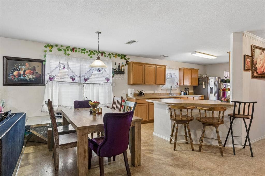 3118 Rosslynn Court, Seagoville, TX 75159 Open-concept kitchen and dining area featuring a breakfast bar, recessed lighting, and wood-finish cabinetry