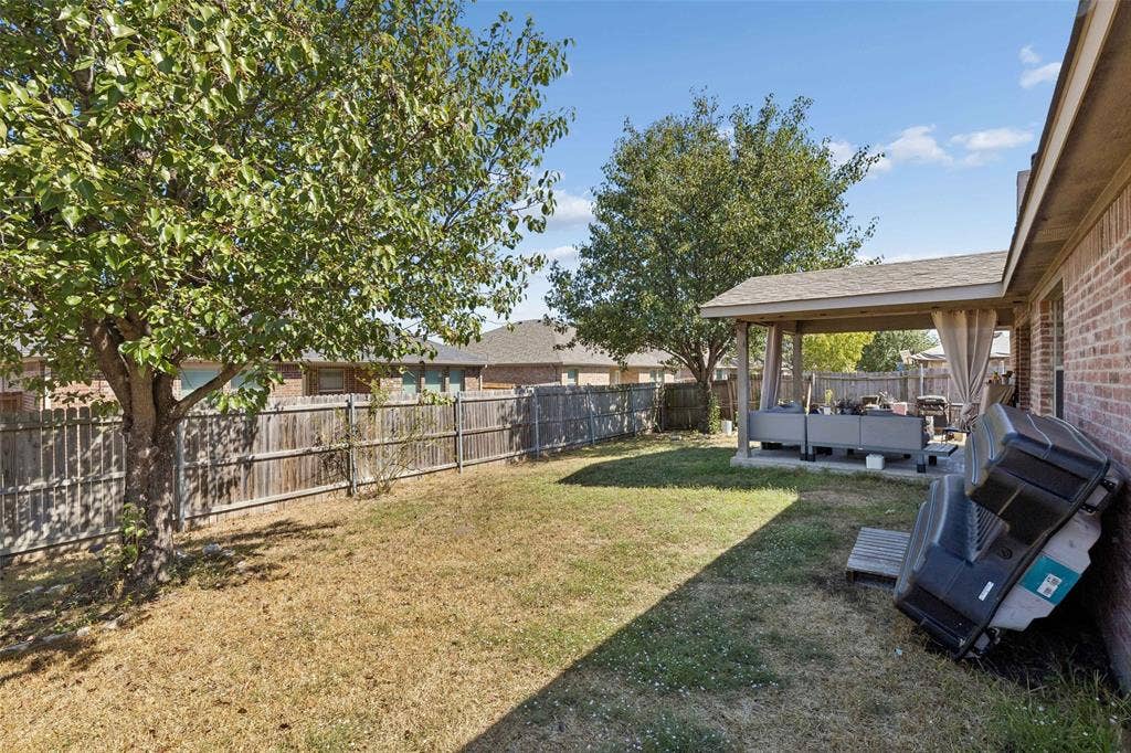 3118 Rosslynn Court, Seagoville, TX 75159 Expansive backyard featuring a covered patio, brick exterior, and a wooden privacy fence