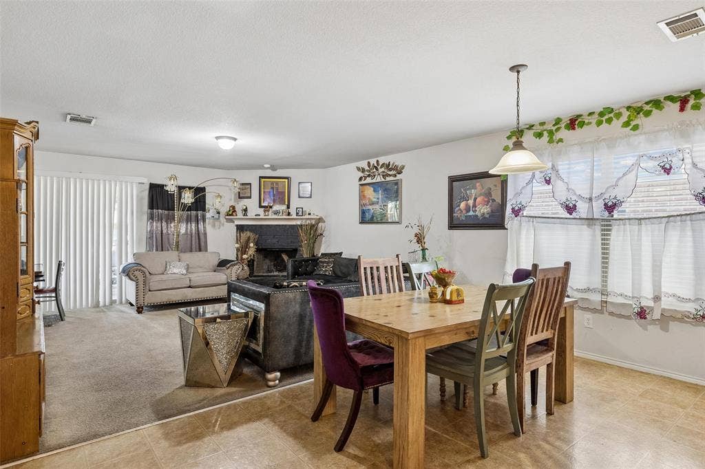 3118 Rosslynn Court, Seagoville, TX 75159 Combined living and dining area featuring a fireplace with a dark mantel, light-toned tile flooring, and a sliding glass door