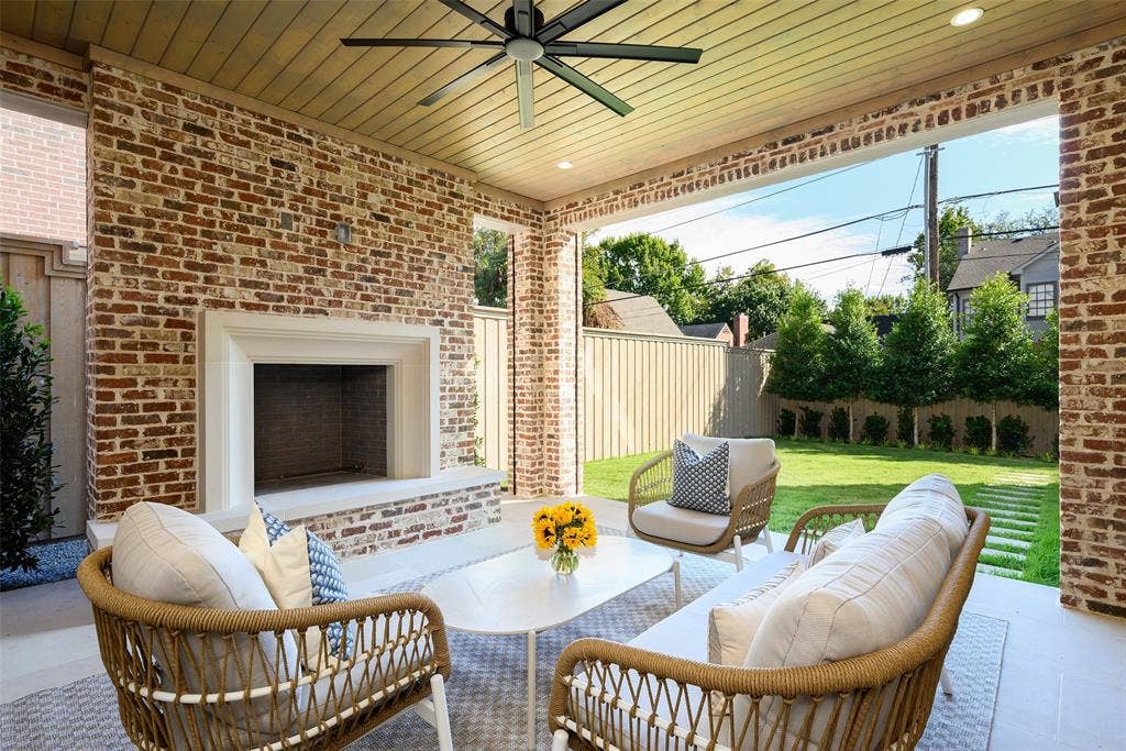 3929 Stanford Avenue, University Park, TX 75225 Rear loggia with large limestone slab flooring, Isokern wood-burning fireplace with raised hearth and cast stone surround, and automated screens