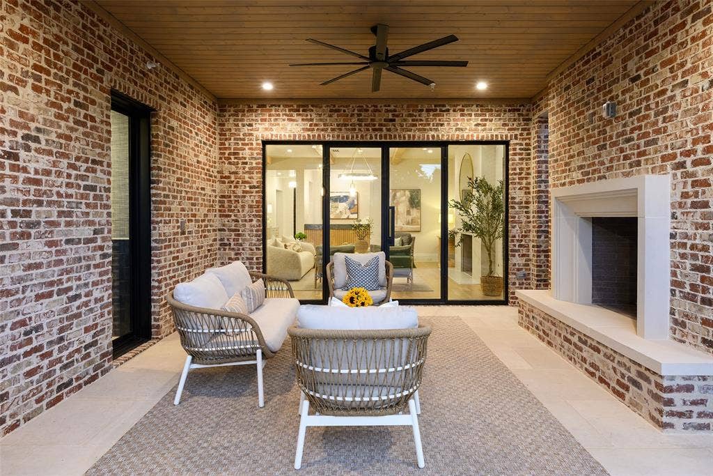 3929 Stanford Avenue, University Park, TX 75225 Rear loggia with large limestone slab flooring, Isokern wood-burning fireplace with raised hearth and cast stone surround, and automated screens