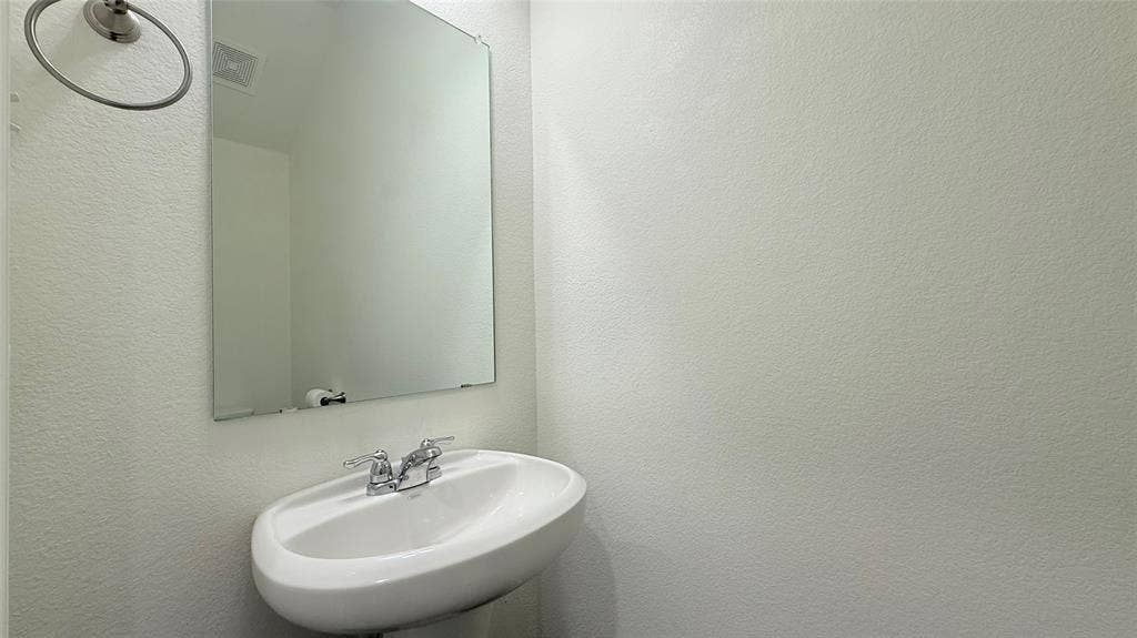 613 Delaware Avenue, Princeton, TX 75407 Pedestal sink with chrome faucet, framed mirror, and wall-mounted towel ring