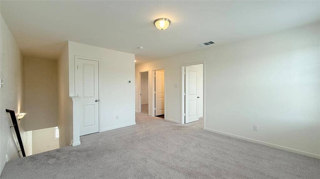 613 Delaware Avenue, Princeton, TX 75407 Expansive carpeted area with white walls, multiple doorways, and an overhead flush-mount light fixture