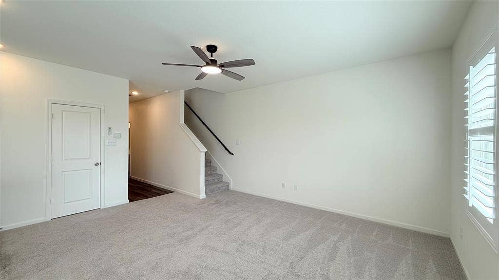 613 Delaware Avenue, Princeton, TX 75407 Open-concept living space featuring light-toned carpeting, a ceiling fan with integrated lighting, and a window with plantation shutters