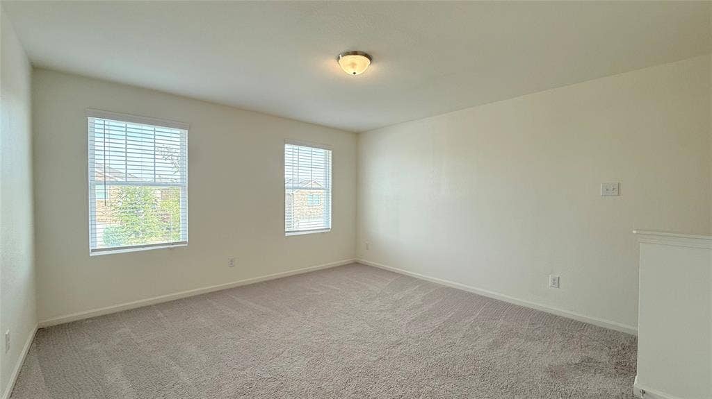 613 Delaware Avenue, Princeton, TX 75407 Carpeted room with two windows featuring blinds, neutral wall paint, and a flush-mount ceiling light fixture