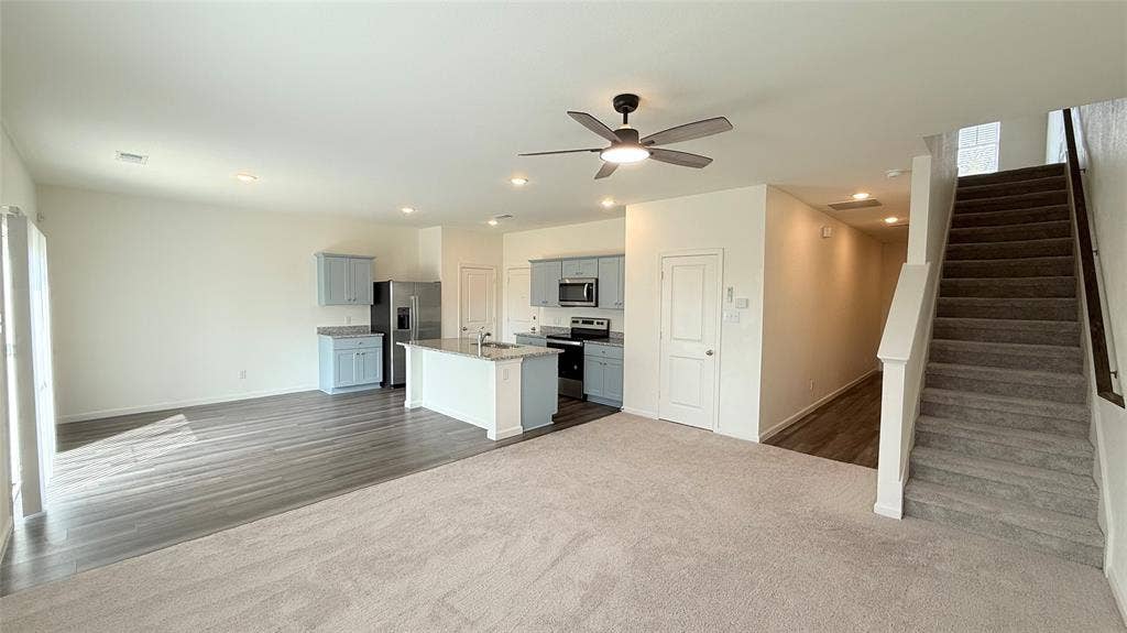 613 Delaware Avenue, Princeton, TX 75407 Open-concept living area featuring a kitchen with light blue cabinetry, an island with countertop seating, stainless steel appliances, and recessed lighting