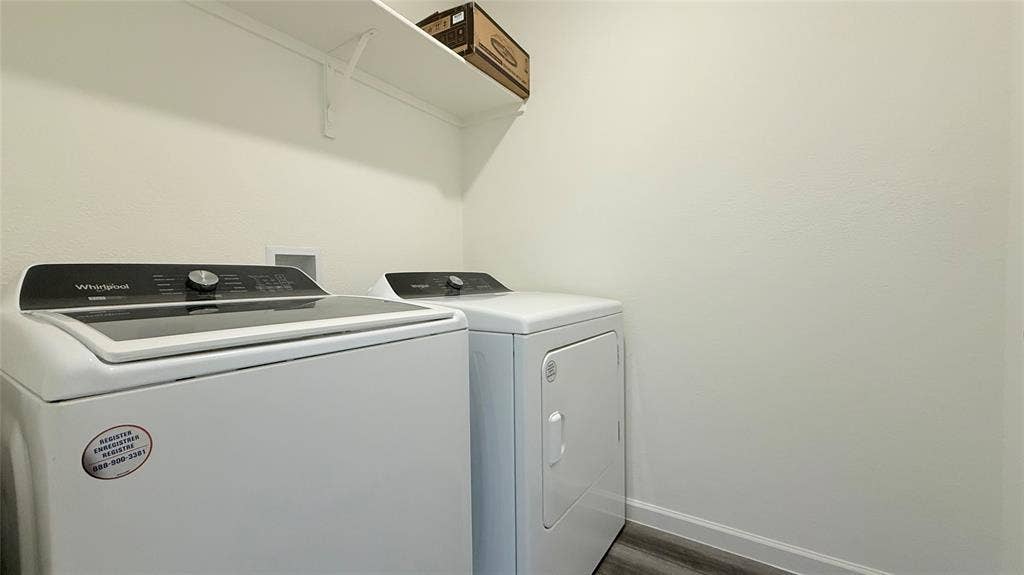 613 Delaware Avenue, Princeton, TX 75407 Dedicated laundry area featuring a washer, dryer, wall-mounted shelving, and wood-finish flooring