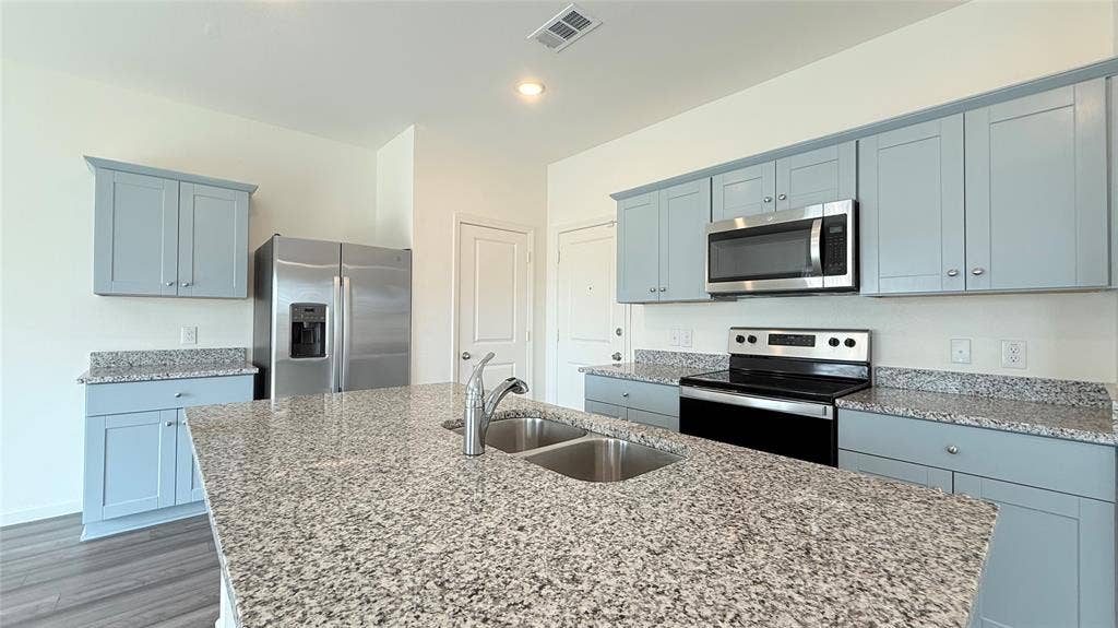 613 Delaware Avenue, Princeton, TX 75407 Kitchen featuring a double basin sink, light-toned cabinetry, stainless steel appliances, and speckled countertops
