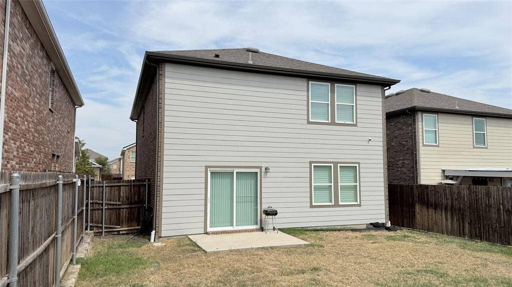613 Delaware Avenue, Princeton, TX 75407 Two-story property featuring light gray siding with contrasting trim, a dark shingle roof, and a concrete patio
