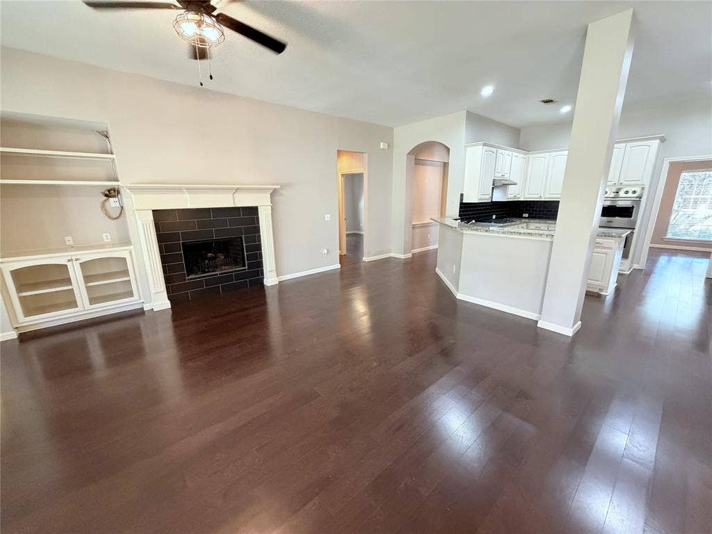 8100 Purple Martin Way, McKinney, TX 75072 Dark wood-finish flooring, built-in shelving, white fireplace mantel with dark tile surround, white cabinetry, and recessed lighting
