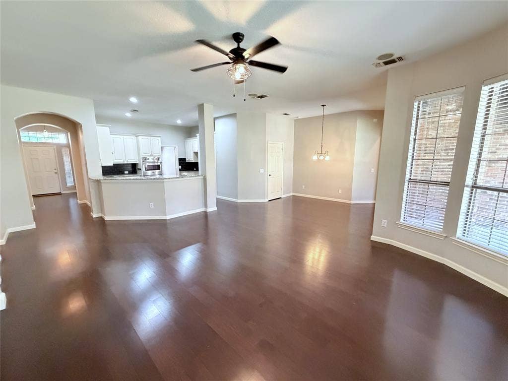 8100 Purple Martin Way, McKinney, TX 75072 Wood-finish flooring throughout, white cabinetry, integrated microwave, pendant lighting, and multiple windows