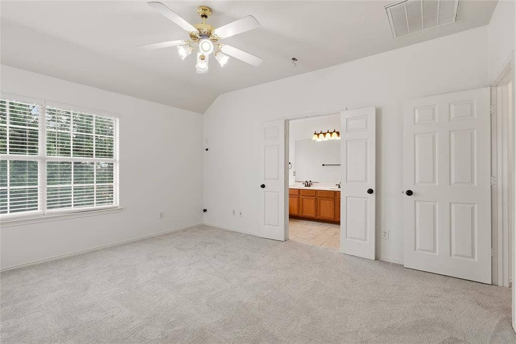 9105 Norman Drive, Plano, TX 75025 Vaulted ceiling with ceiling fan, large window with blinds, light-toned carpeting, and panel doors