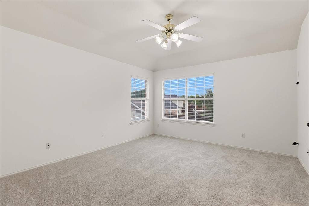 9105 Norman Drive, Plano, TX 75025 Room featuring carpet flooring, two windows with blinds, and a ceiling fan with integrated lighting
