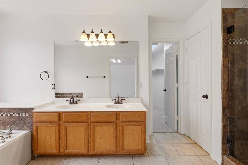 9105 Norman Drive, Plano, TX 75025 Dual vanity with integrated sinks, wood cabinetry, and a full-width mirror