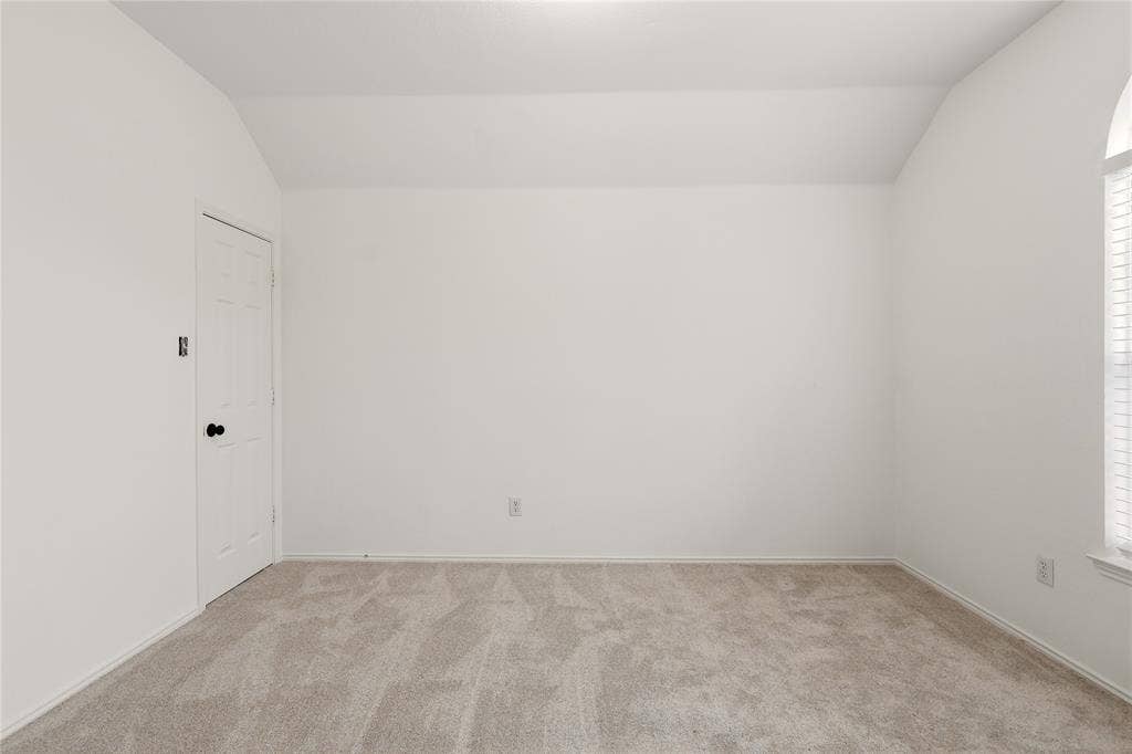 9105 Norman Drive, Plano, TX 75025 Carpeted flooring, vaulted ceiling, arched window with horizontal blinds, and a paneled door with black hardware