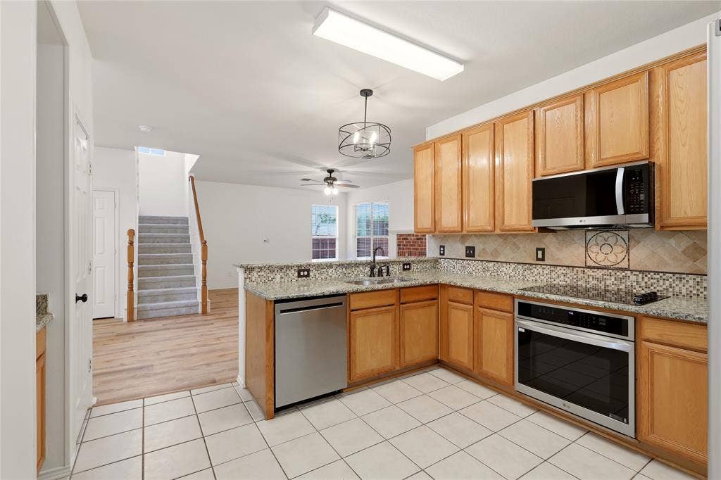 9105 Norman Drive, Plano, TX 75025 Kitchen featuring wood cabinetry, stainless steel appliances, granite countertops, and tiled flooring