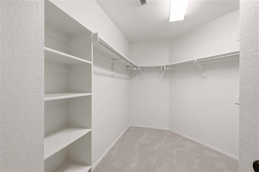 9105 Norman Drive, Plano, TX 75025 Walk-in closet featuring white shelving, multiple hanging rods, and light-toned carpeting