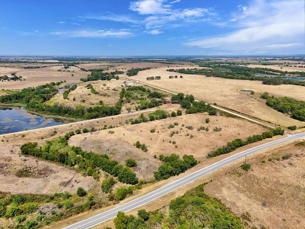 TBD Horne Hill Road, Moody, TX 76557 Expansive rural landscape featuring a paved road, natural water body, and scattered trees